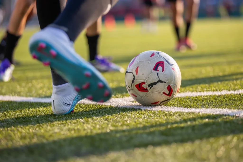 Close-up of a football boot about to strike the ball next to the touchline