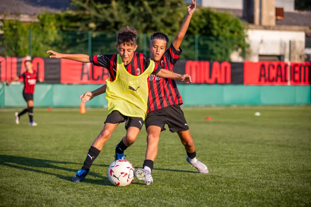 Two boys challenging for the ball during a training match, one in a yellow bib