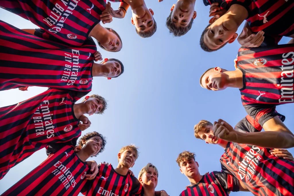 Low-angle view of young players in a huddle looking down at the camera against a blue sky